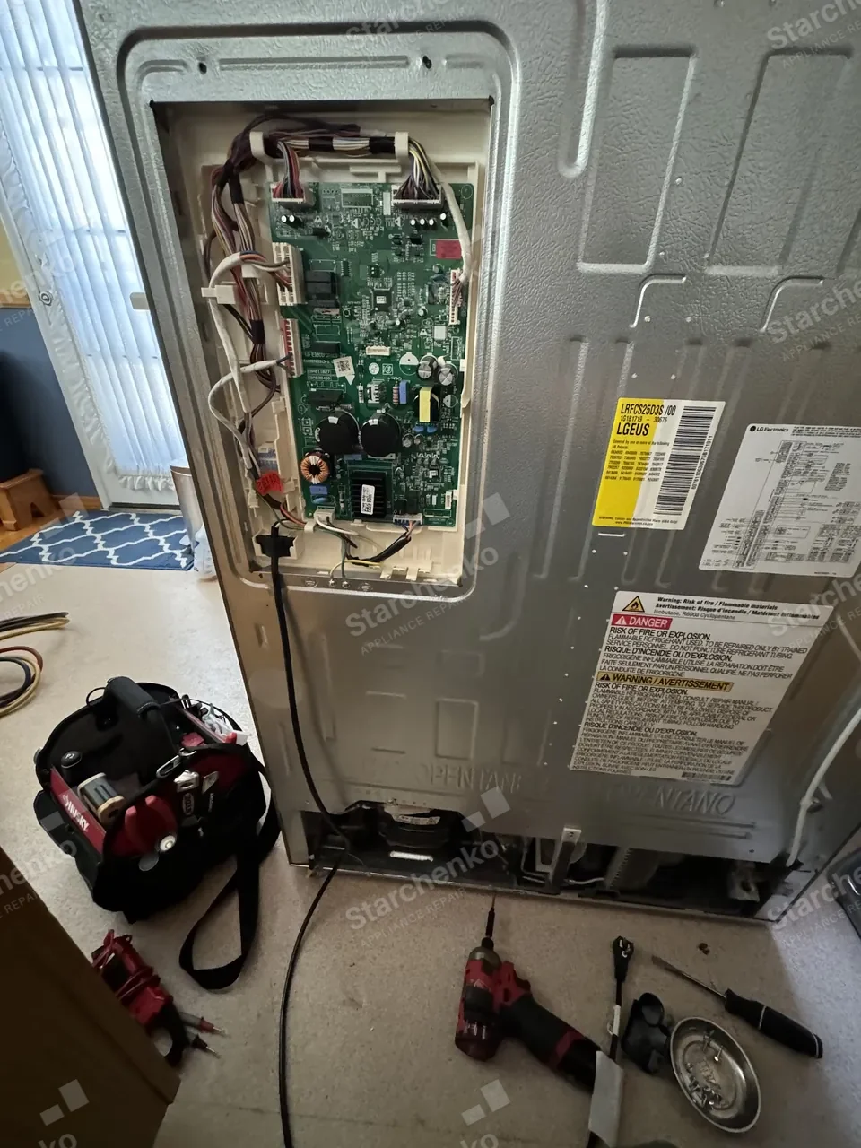 LG refrigerator pulled out from the wall with the back panel removed and the inverter board exposed