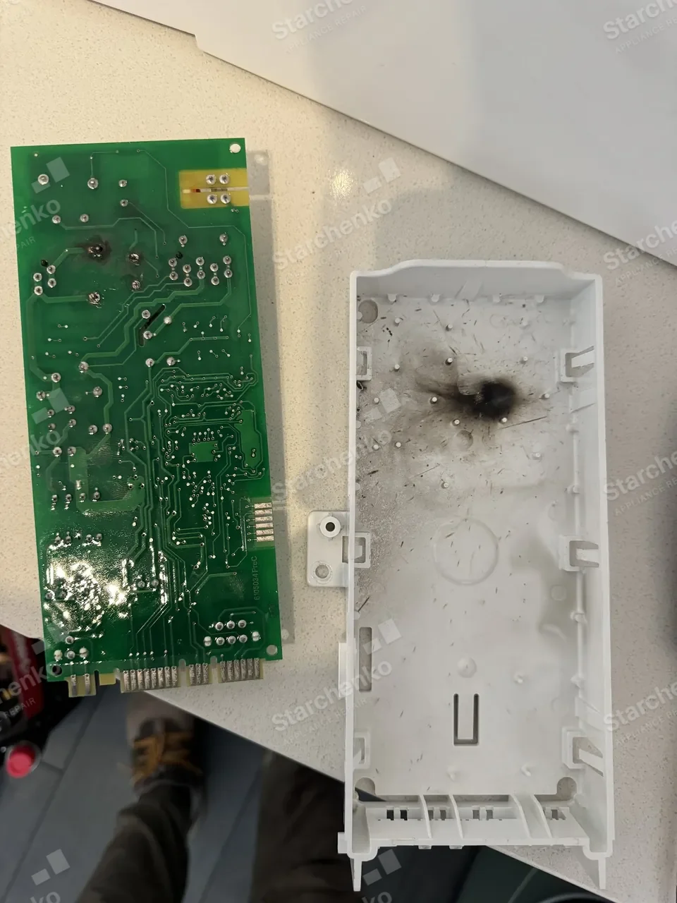 Jenn-Air microwave control board with a burnt track, taken out and laid next to its housing