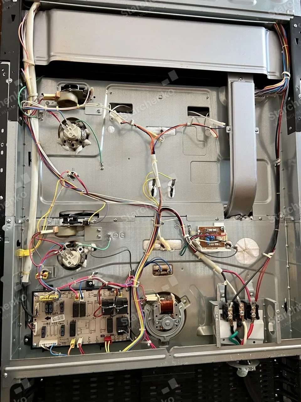 Miele range with the rear service panel off: wiring harness, control board and the cooling fan exposed