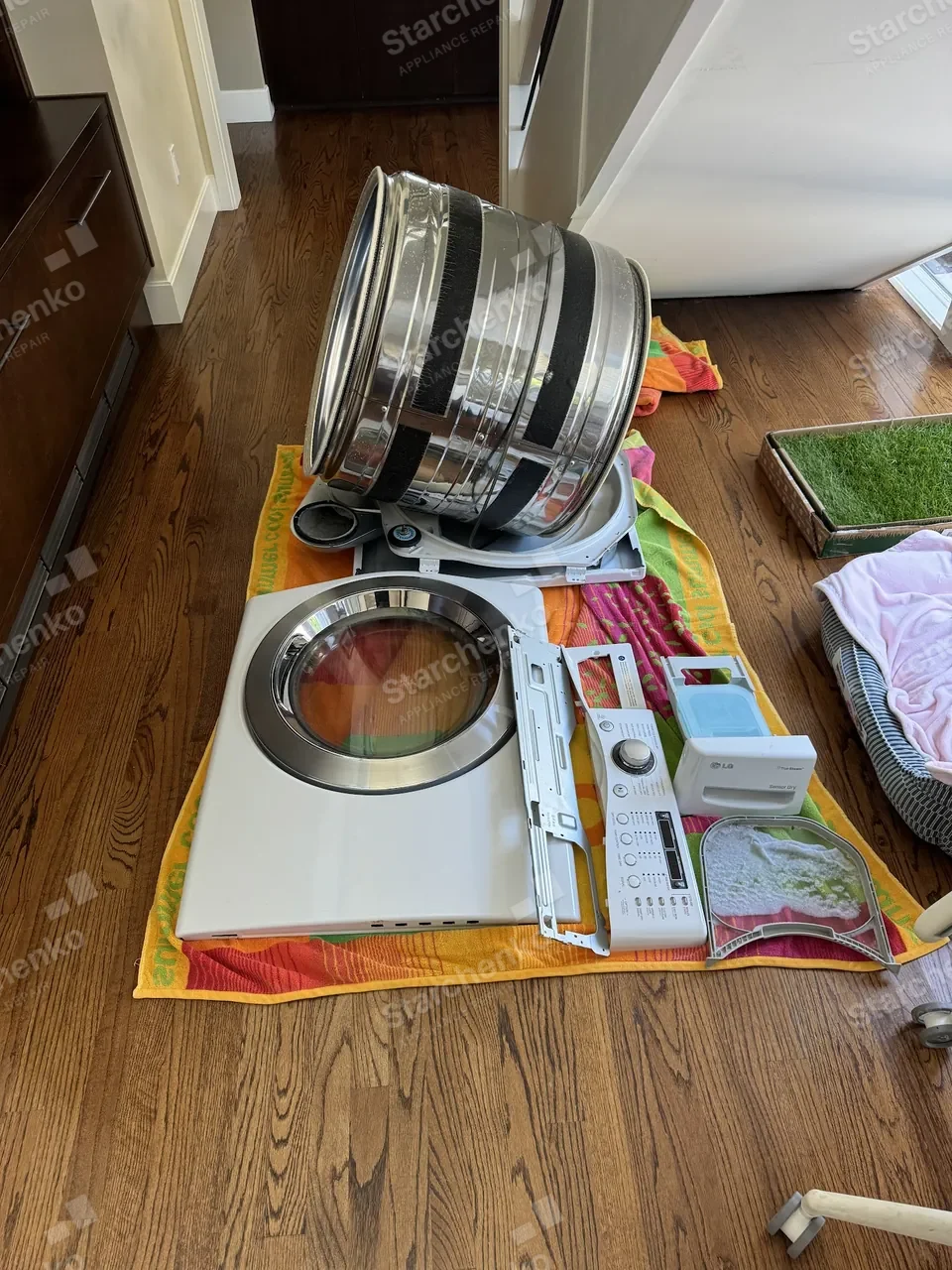 LG dryer taken apart on the floor: the drum out of the cabinet with the front panel beside it